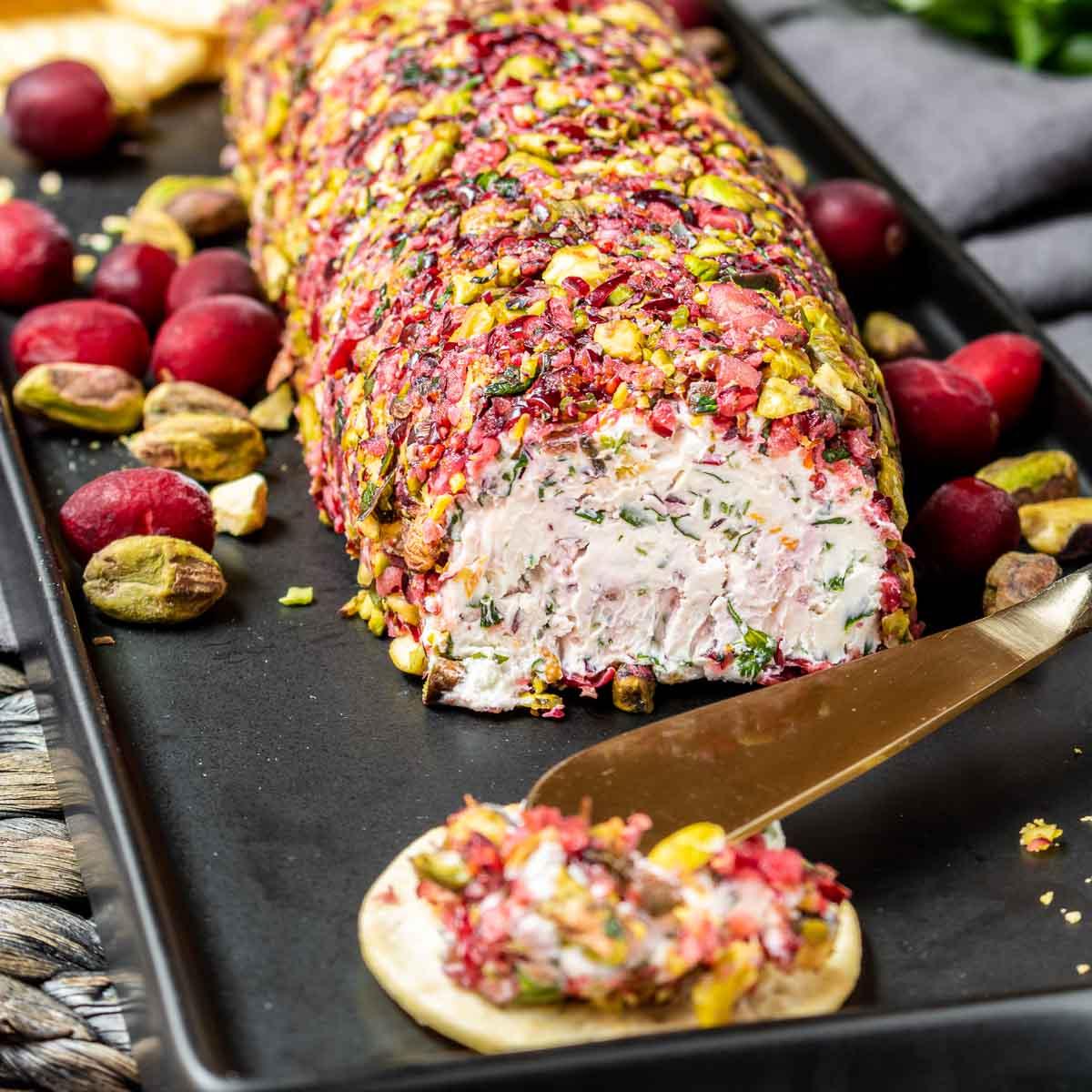 Preiselbeer-Ziegenkäse-Rolle 2 Ziegenkäse-Log auf schwarzer Platte mit Preiselbeeren