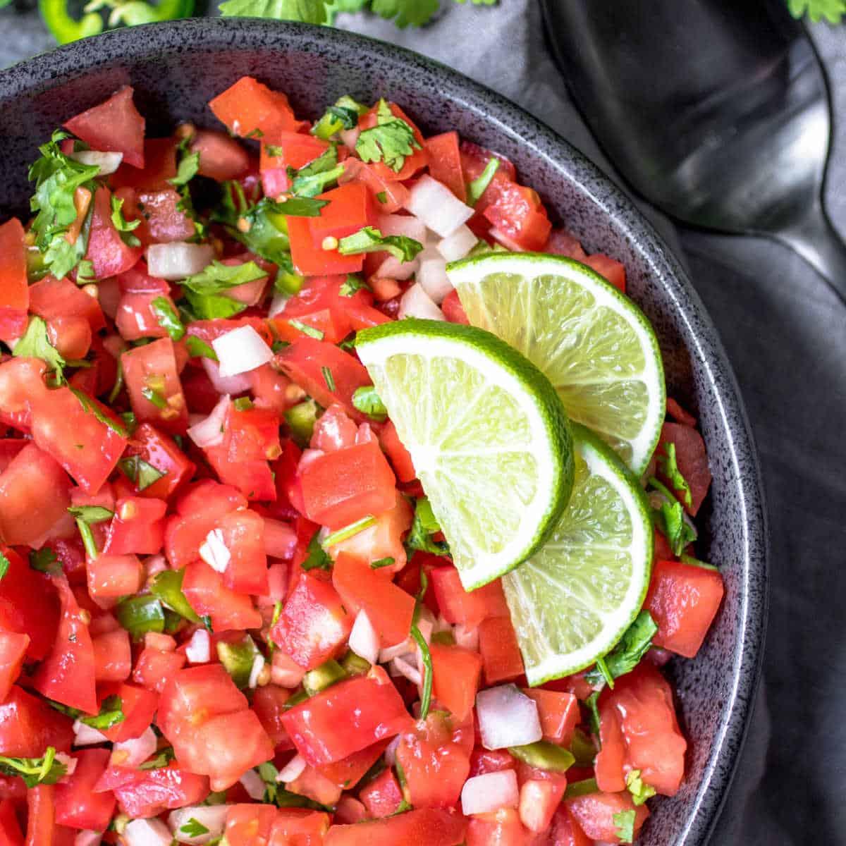 Salsa Fresca {Frische Tomatensalsa} 2 Salsa Fresca in einer schwarzen Schüssel mit drei Limettenspalten