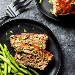 Keto Hackbraten – Low-Carb-Soulfood 11 Keto Hackbraten auf einem Teller mit grünen Bohnen und einer Gabel.
