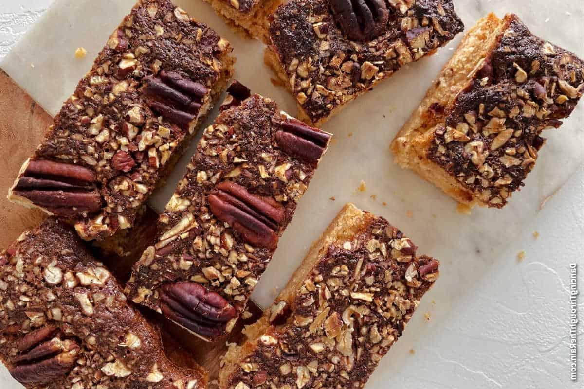 Unwiderstehliche Desserts mit Pekannusskuchenfüllung 12 Geschnittene Pekannuss-Riegel, angeordnet auf einer weißen Oberfläche.