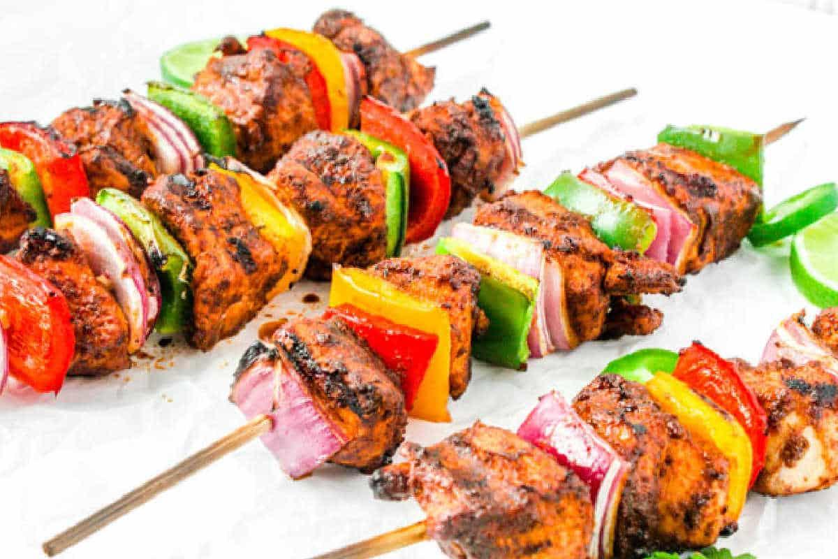Festliche Abendessenrezepte für den Cinco de Mayo 12 Gegrillte Hähnchen-Fajita-Spieße mit Paprika und Zwiebeln, serviert auf einem Teller.