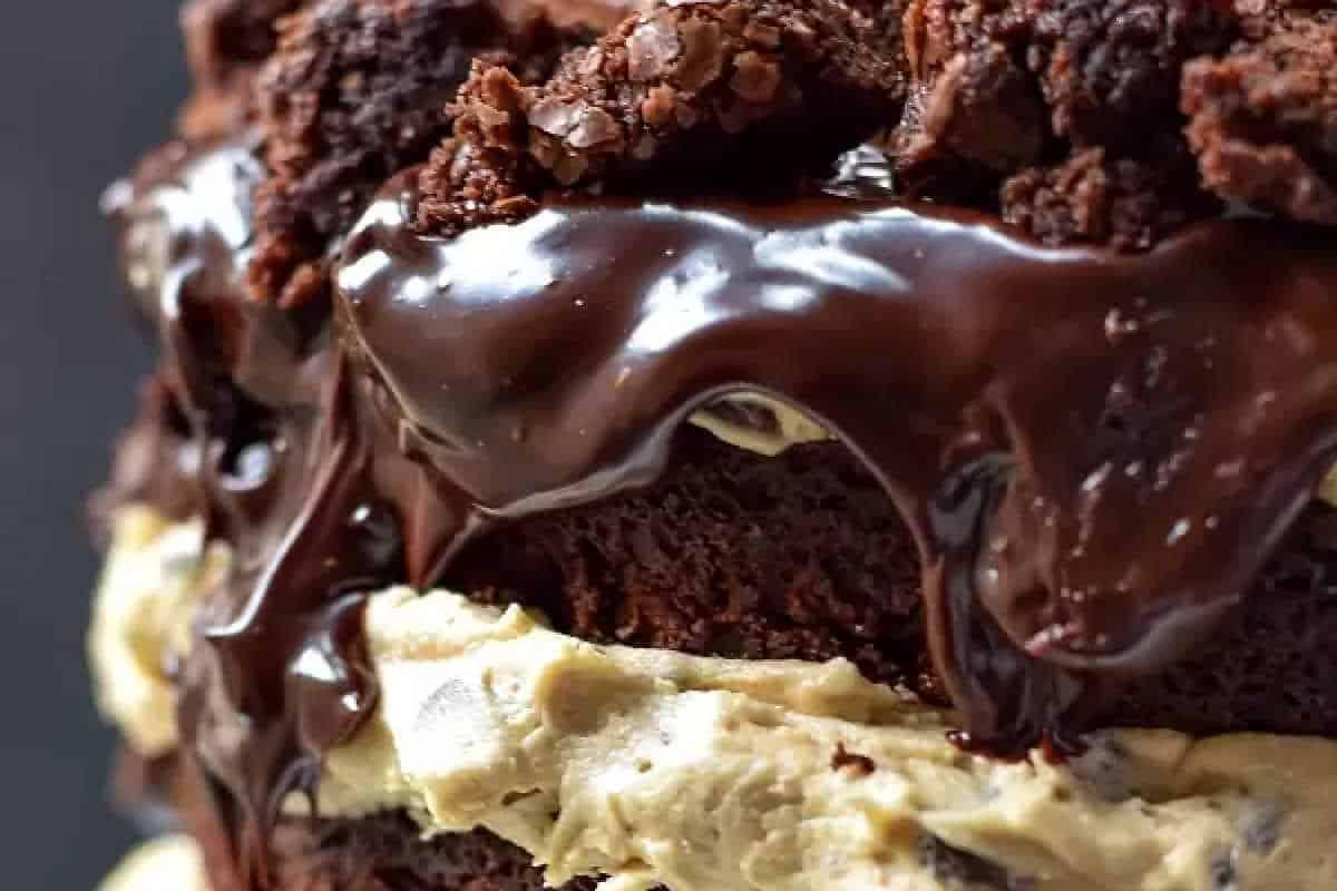 **Ein Galentine’s-Schmaus für deine Mädels** 19 Nahaufnahme eines Schokoladenkuchens mit reichhaltiger Schokoladenglasur und Keksteigfüllung, belegt mit zerbröselten Schokoladenstücken.