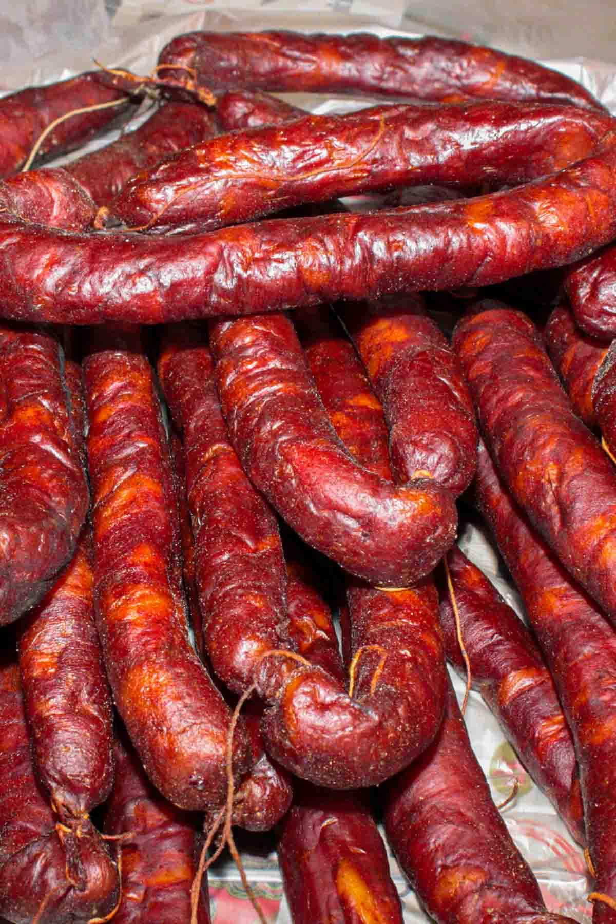 Hausgemachtes Chouriço herstellen: Eine traditionelle portugiesische Wurst 3 Ein Stapel getrockneter portugiesischer Wurst auf einem Tisch.