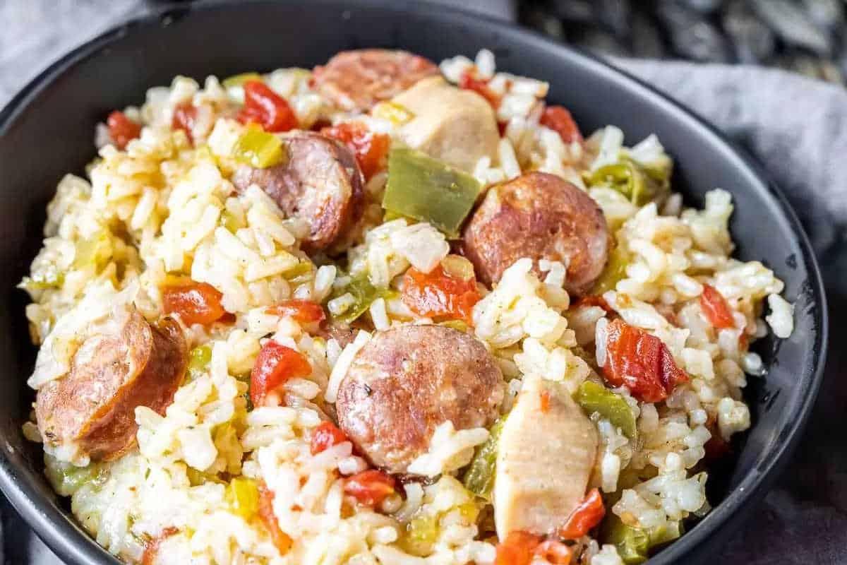 33 einfache und günstige Gerichte (die Ihre Familie auch wirklich essen möchte) 23 Eine Schale Reis, gemischt mit geschnittenen Würstchen, Hühnchen, gewürfelten Tomaten und grüner Paprika.