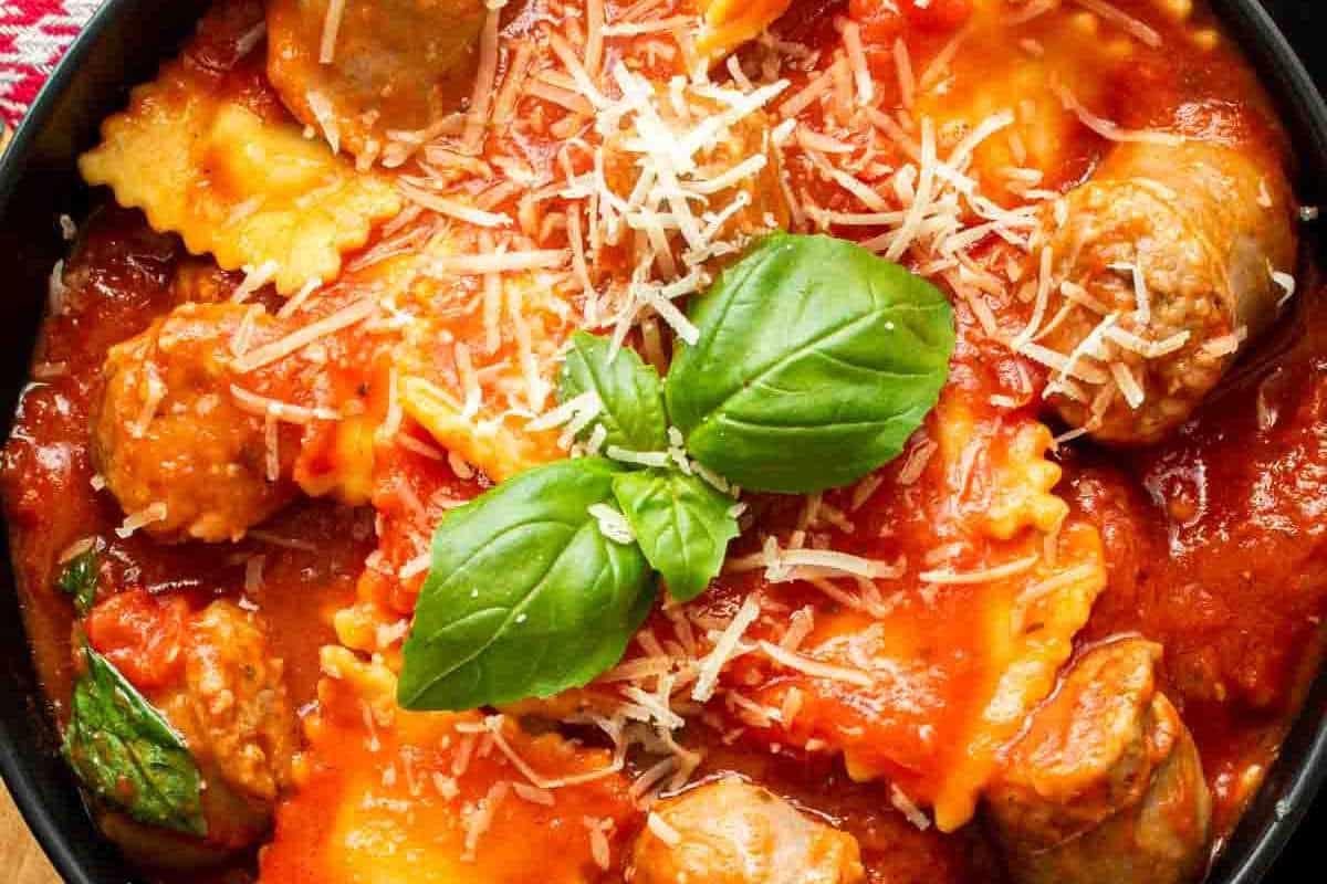33 einfache und günstige Gerichte (die Ihre Familie auch wirklich essen möchte) 29 Eine Schale Ravioli in Tomatensauce mit Fleischbällchen, belegt mit geriebenem Parmesan und frischen Basilikumblättern.