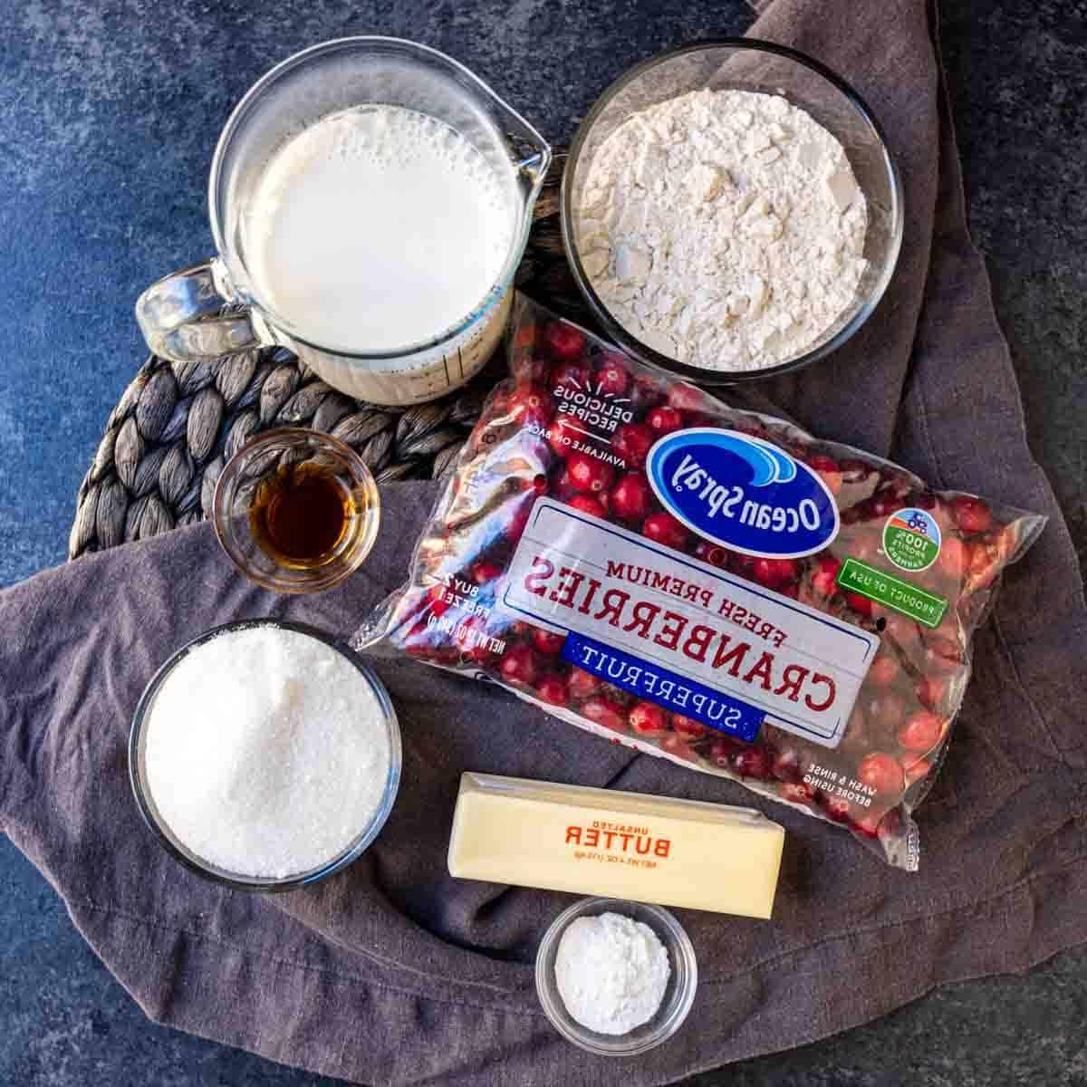 Cranberry-Streuselkuchen 4 Zutaten auf einem Tisch: Mehl, Milch, frische Preiselbeeren, Vanilleextrakt, Zucker und ein Stück Butter.
