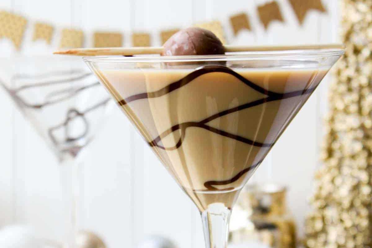 **Ein Galentine’s-Schmaus für deine Mädels** 4 Ein Schokoladen-Martini-Glas mit Schokoladensirup-Wirbeln, garniert mit einer Schokoladentrüffel und Waffelstange. Verschwommener dekorativer Hintergrund.