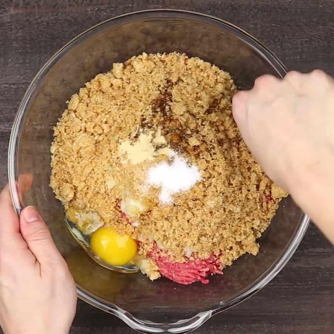 Keto Hackbraten – Low-Carb-Soulfood 4 Eine Person mischt sorgfältig die Zutaten für den ketogenen Hackbraten in einer großen Schüssel.