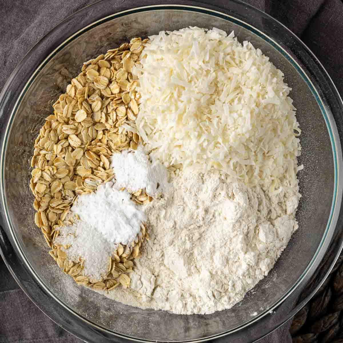 Knusprige Kokos-Haferflocken-Spitzenplätzchen 4 Haferflocken, Mehl, Zucker und Butter in einer Glasschüssel zur Herstellung von knusprigen Kokos-Keksen