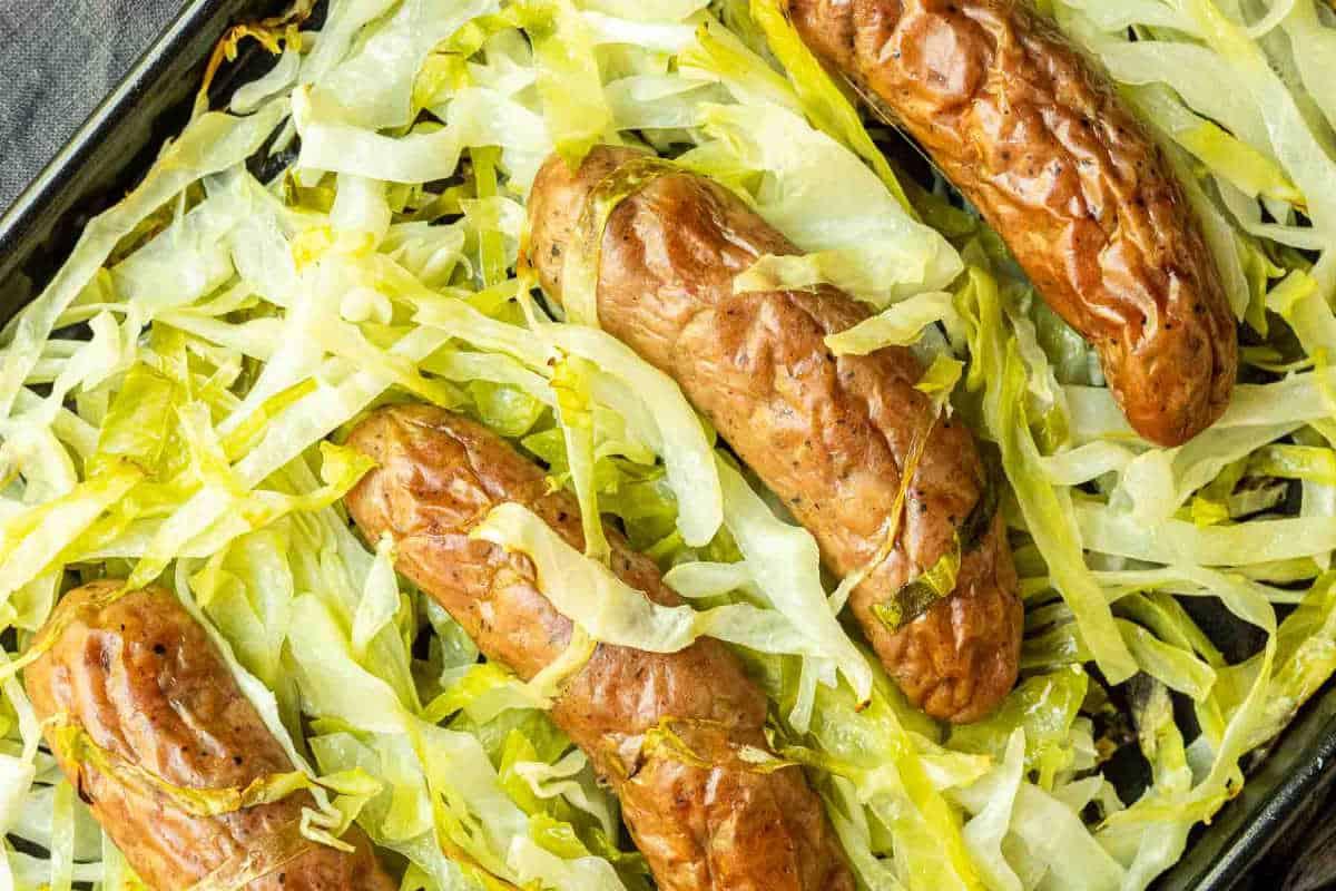 33 einfache und günstige Gerichte (die Ihre Familie auch wirklich essen möchte) 32 Vier gekochte Würstchen liegen auf einem Backblech mit zerkleinertem Kraut.