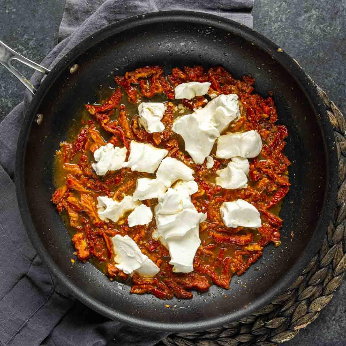 Cremige Florentiner Hähnchen-Pasta 5 Tomatensauce mit Käseklümpchen in einer Bratpfanne für Hähnchen Florentiner Auflauf.