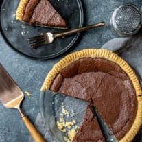 Schokoladen-Chess-Pie 6 ganzer Schokoladen-Chess-Pie und Scheibe auf einem Teller