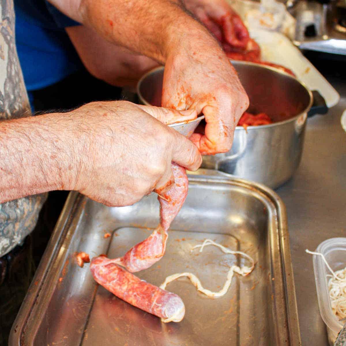 Hausgemachtes Chouriço herstellen: Eine traditionelle portugiesische Wurst 6 Ein Mann bereitet portugiesische Wurst in einer Pfanne zu.