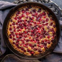 Cranberry-Streuselkuchen 7 Ein gebackenes Dessert mit goldener Kruste und roten Preiselbeeren in einer Gusseisenpfanne.