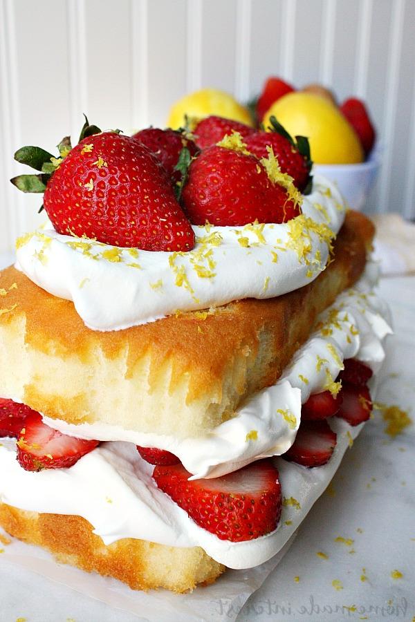 Ein köstlicher, dreilagiger No-Bake Erdbeer-Sommerkuchen, bereit zum Servieren auf einer festlichen Tafel. Dieser Kuchen ist ein perfektes Dessert für den Sommer, da er schnell zubereitet ist und ohne Backen auskommt, ideal für jede Feier oder spontane Gäste.