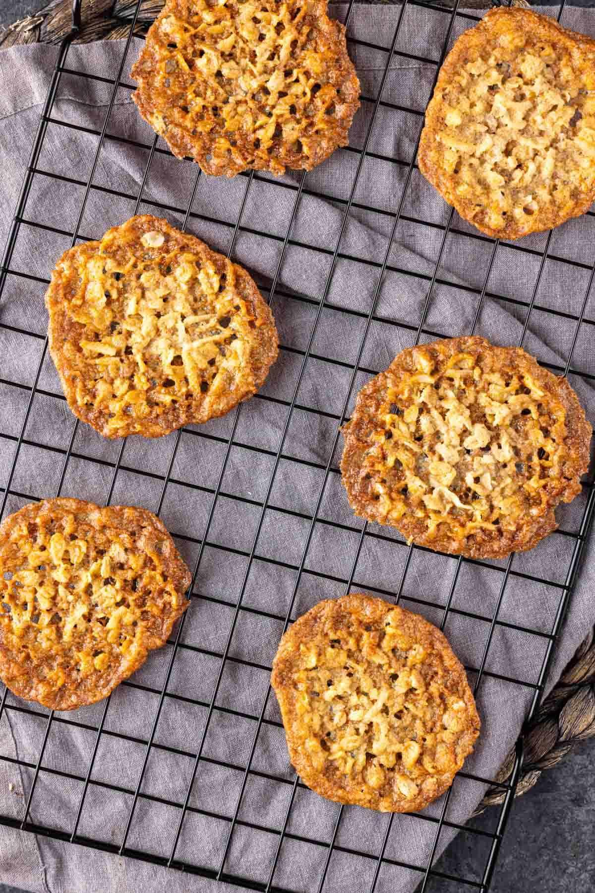 Knusprige Kokos-Haferflocken-Spitzenplätzchen 7 Knusprige Kokos-Kekse auf einem Abkühlgitter.