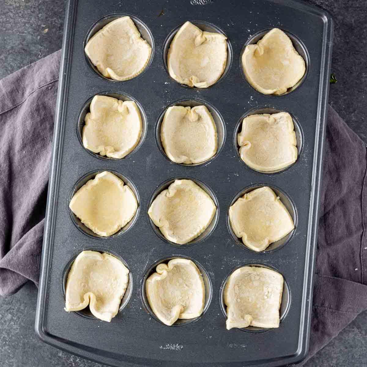 Spinat-Blätterteig-Vorspeise 7 Ein Muffinblech gefüllt mit Teig für Spinat-Blätterteig-Häppchen