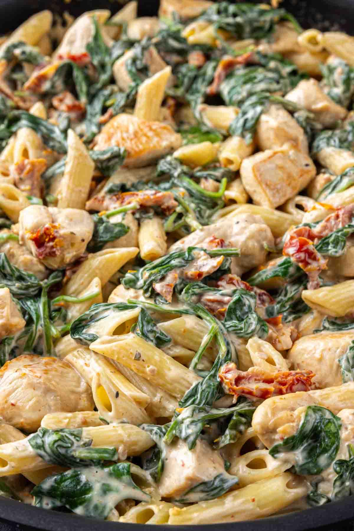 Cremige Florentiner Hähnchen-Pasta 8 Cremiger Hähnchen Florentiner Auflauf, Spinat und sonnengetrocknete Tomaten in einer Pfanne.