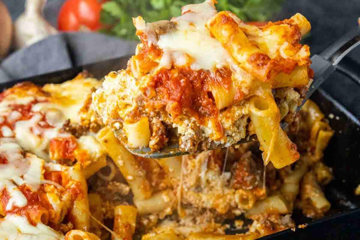 33 einfache und günstige Gerichte (die Ihre Familie auch wirklich essen möchte) 9 Ein Teller mit gebackenen Ziti-Nudeln mit geschmolzenem Käse und Tomatensauce, der aus einer Backform gehoben wird.