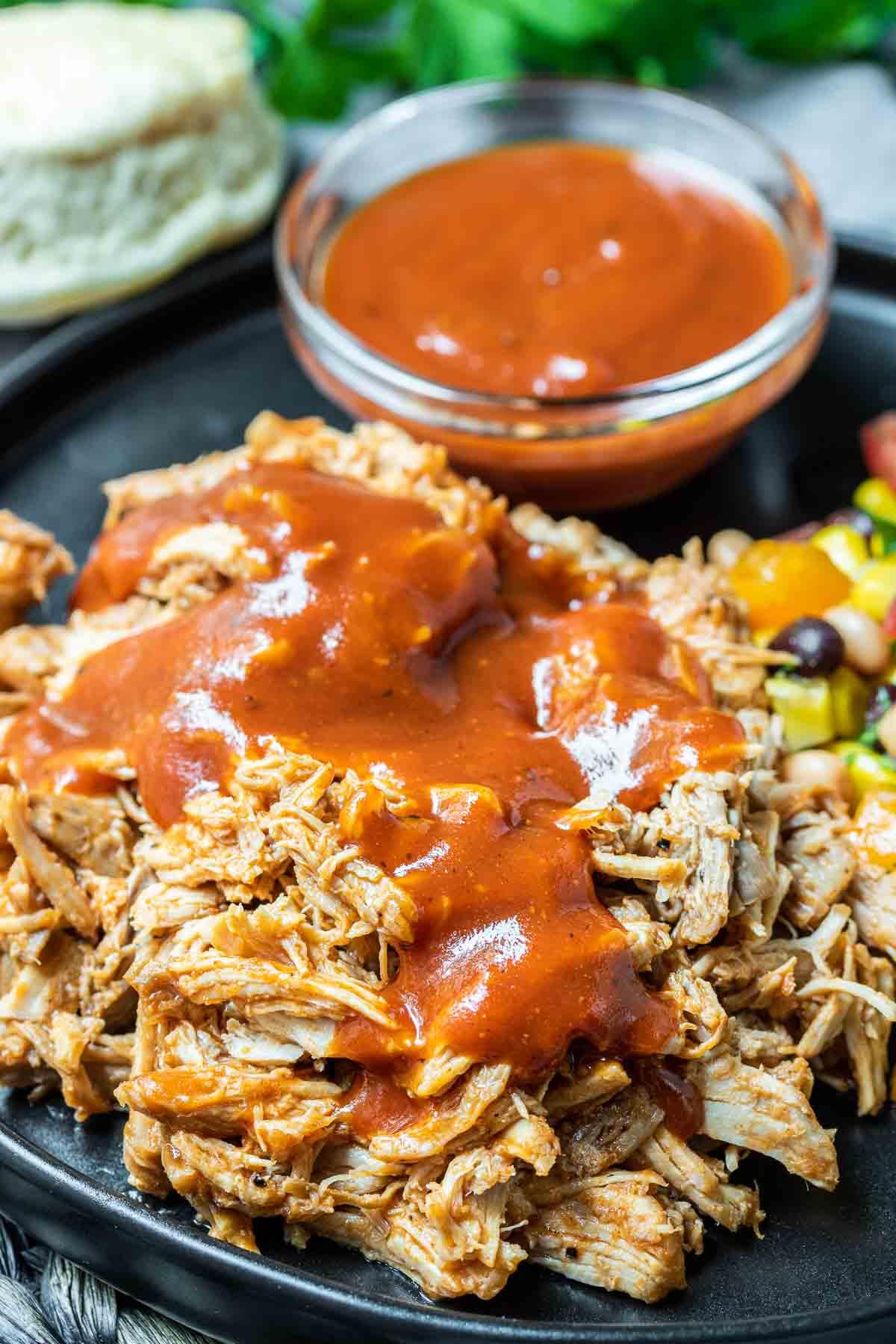 **Schnellkochtopf Pulled Pork** 9 Pulled Pork aus dem Schnellkochtopf auf einem Teller mit BBQ-Sauce im Hintergrund
