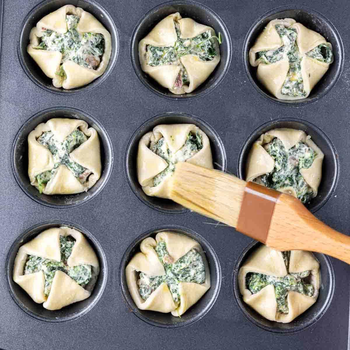 Spinat-Blätterteig-Vorspeise 8 Eine Pfanne voll Spinat-Blätterteig-Häppchen in einem Muffinblech.