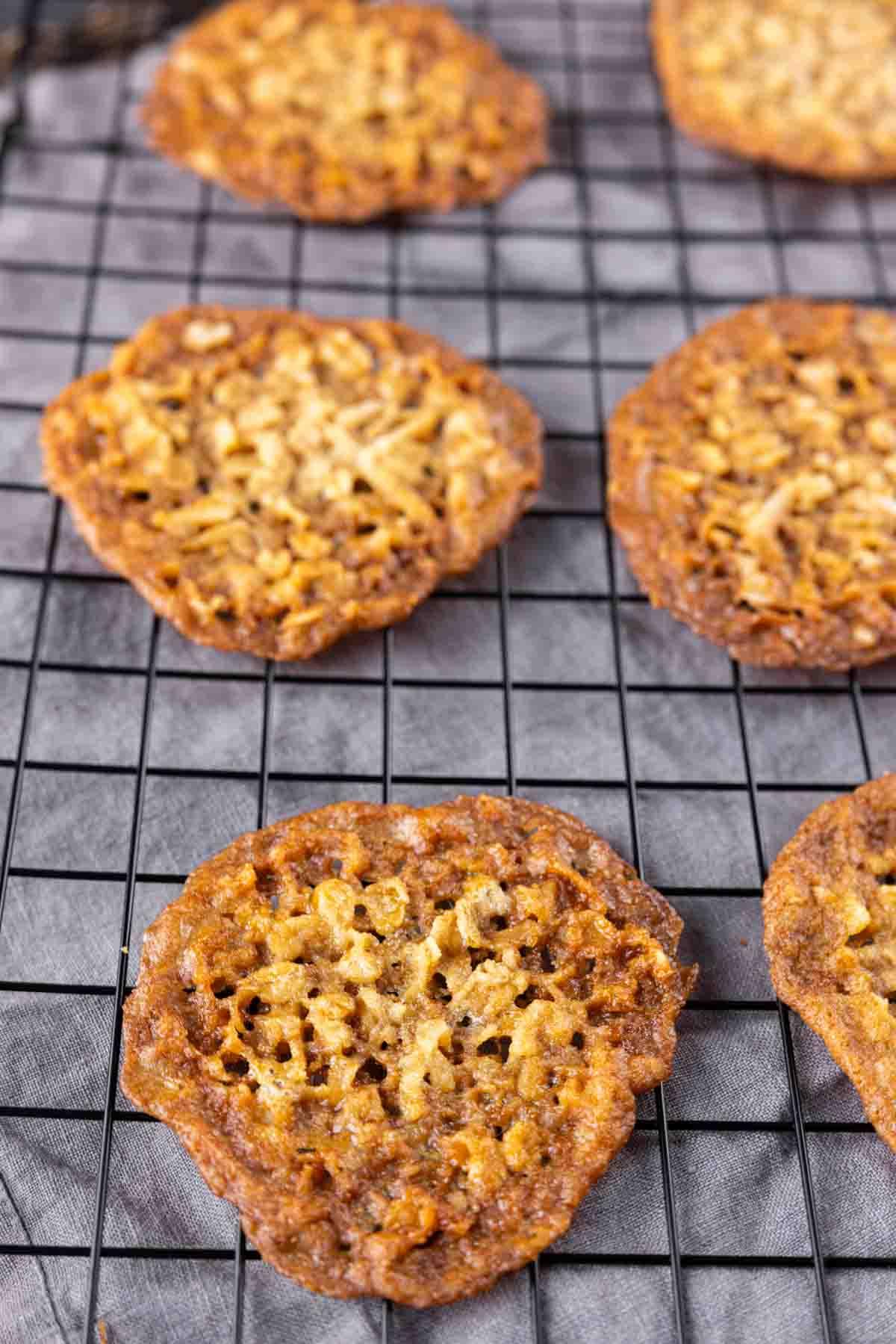 Knusprige Kokos-Haferflocken-Spitzenplätzchen 9 Knusprige Kokos-Kekse auf einem Abkühlgitter.