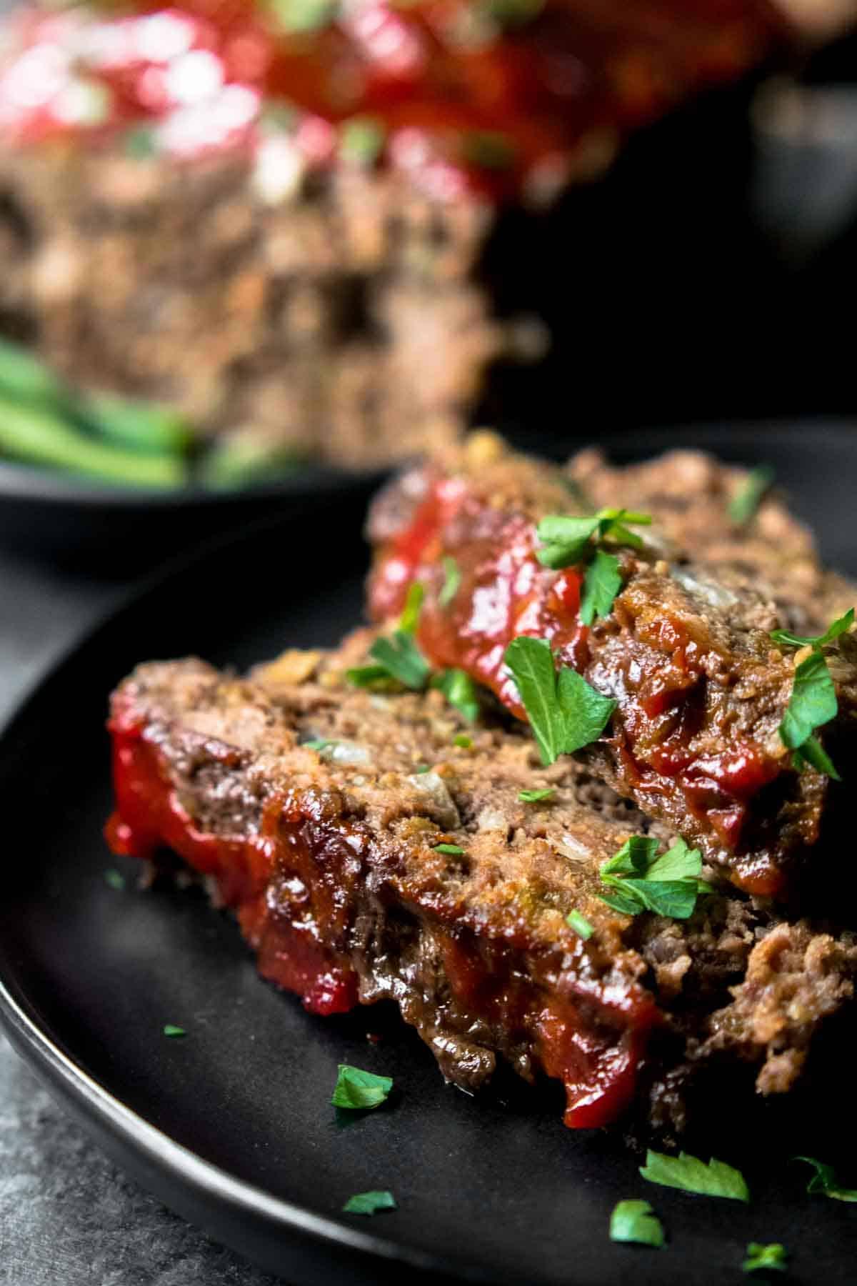 Keto Hackbraten – Low-Carb-Soulfood 10 Ein perfekt gebackenes Stück ketogener Hackbraten auf einem schwarzen Teller, bereit zum Servieren.