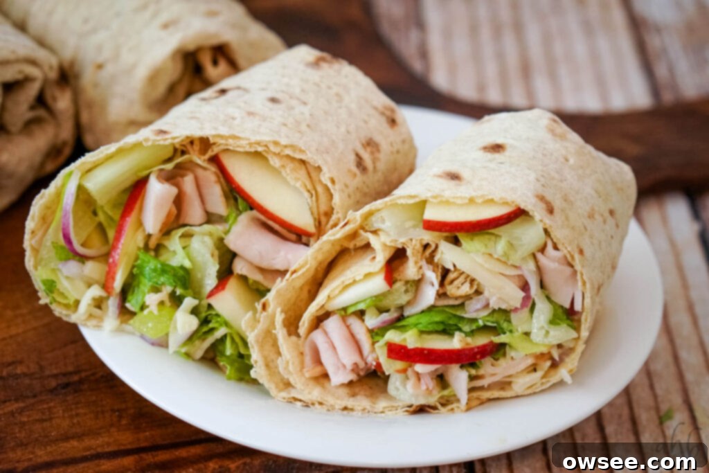 Crisp Turkey Apple Swiss Wraps 11 A complete Turkey Swiss and Apple Wrap cut in half and served on a white plate.