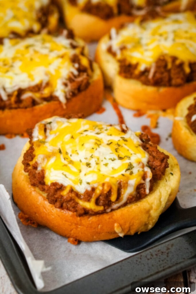 Sloppy Joe Stuffed Garlic Bread 3 A Garlic Bread Sloppy Joe being scooped off of a baking sheet with a black spatula, showing the rich filling.