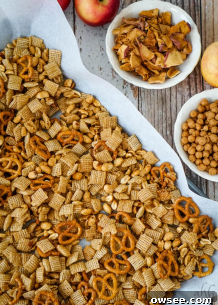 Golden Apple Caramel Crunch 8 The cereal mixture is laid out on a baking tray to cool next toa bowl of apple chips and a bowl of caramel chips.