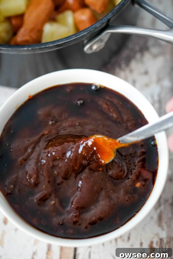 Hawaiian Little Smokies 6 The sweet chili sauce, barbecue sauce, and soy sauce are stirred together with a fork in a bowl.