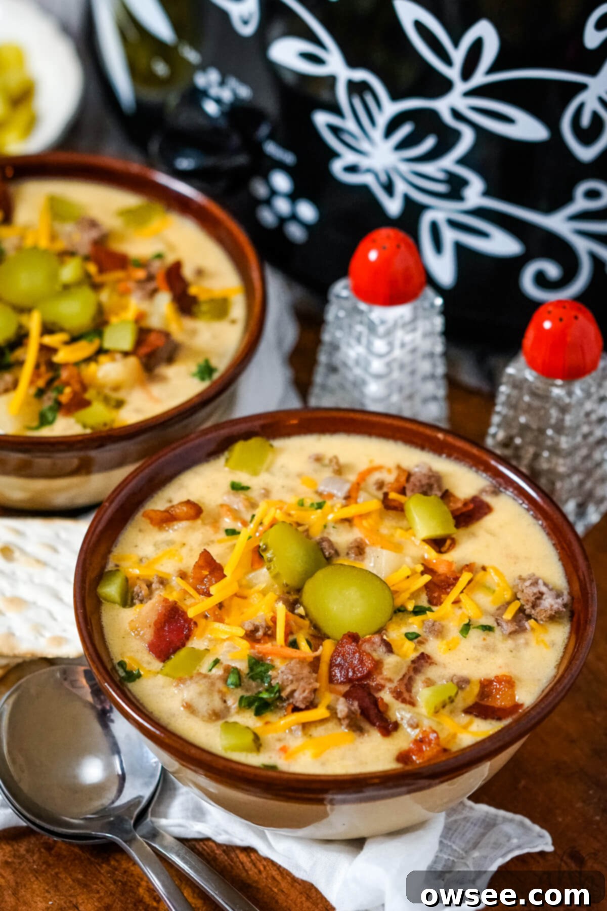 Creamy Slow Cooker Bacon Cheeseburger Soup 3 Two bowls of slow cooker bacon cheeseburger soup on a serving tray next to a slow cooker.