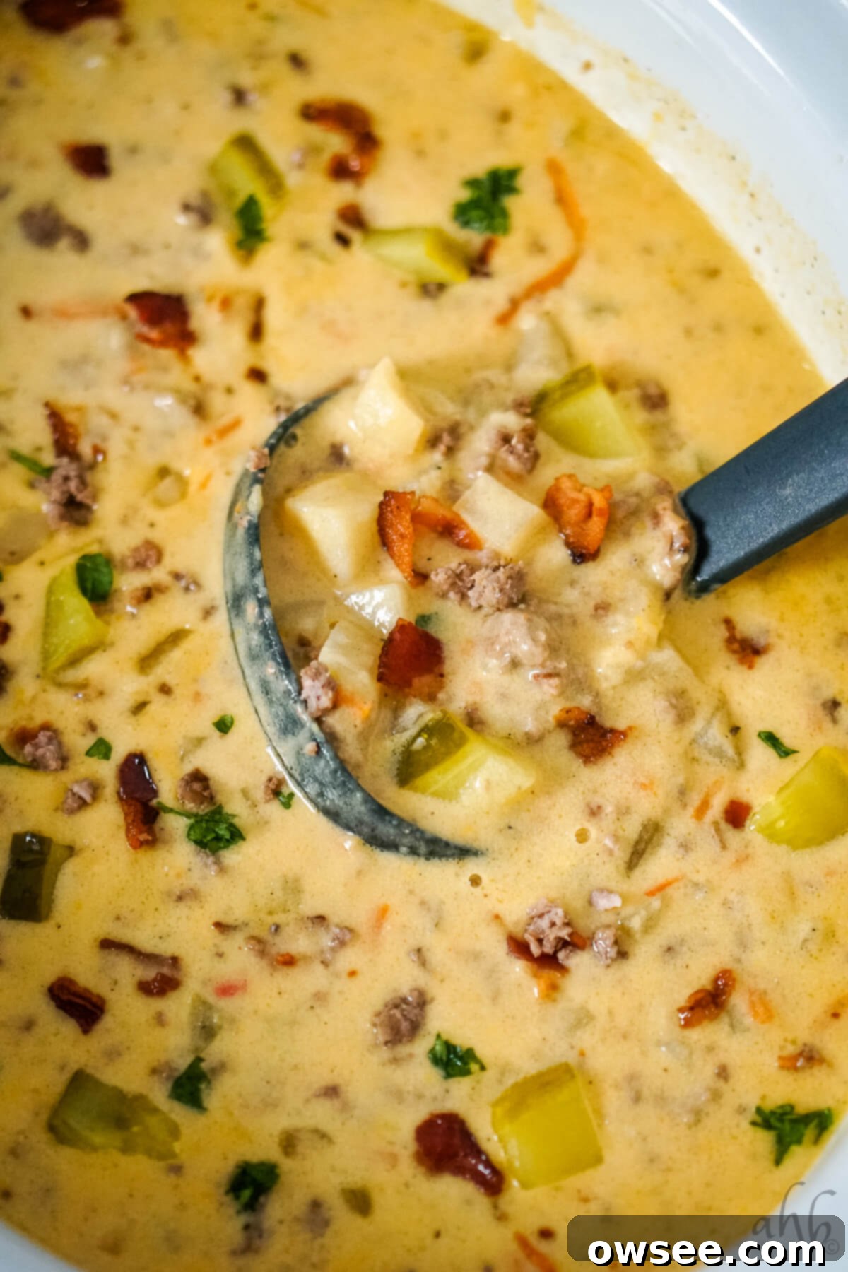 Creamy Slow Cooker Bacon Cheeseburger Soup 4 A ladle stirring Bacon Cheeseburger Soup in the slow cooker.