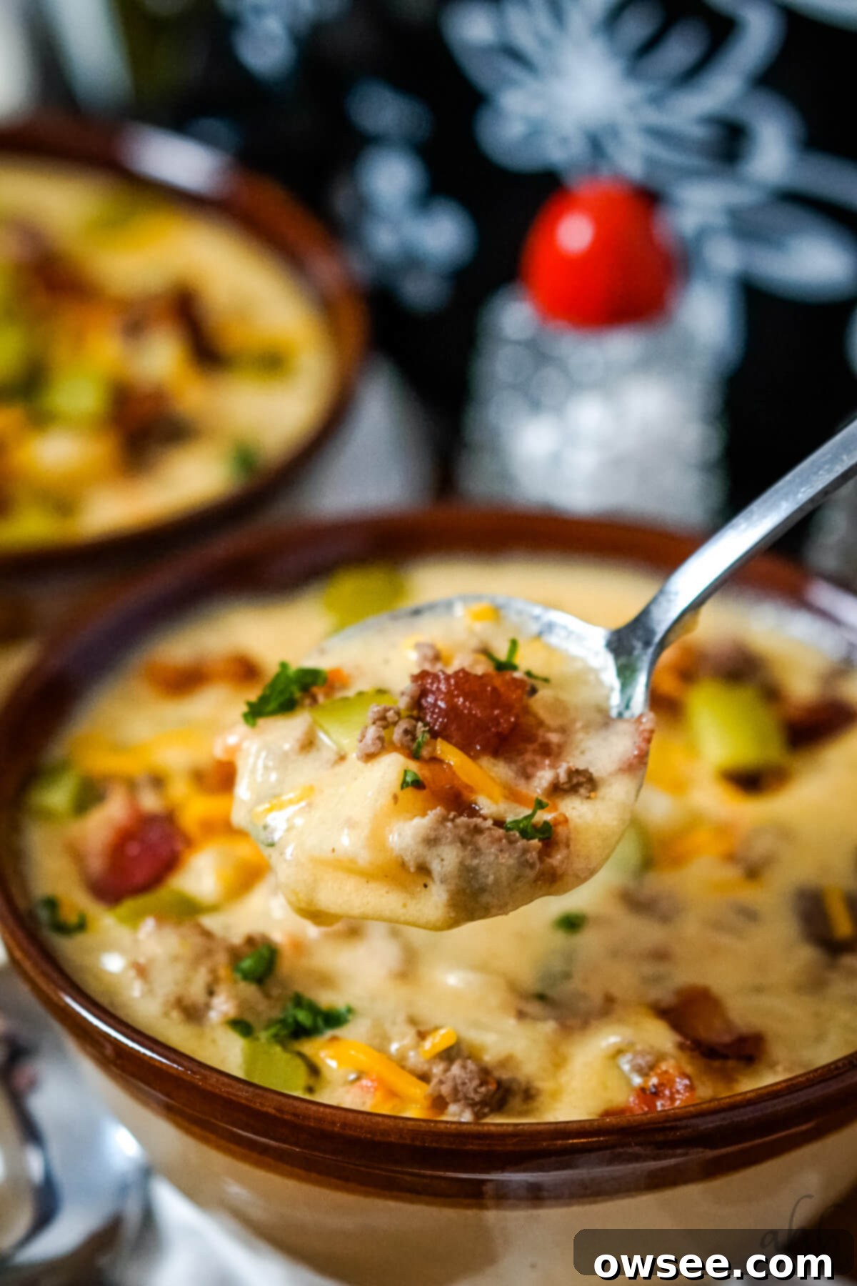 Creamy Slow Cooker Bacon Cheeseburger Soup 5 A close up image of a spoon full of slow cooker bacon cheeseburger soup.