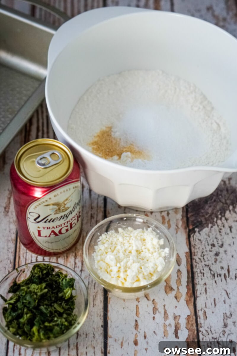 Savory Spinach Feta Beer Bread 5 A bowl of the dry ingredients next to a can of beer, a bowl of feta cheese, and a bowl of spinach.