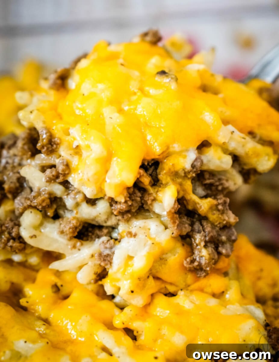 Savory Beef and Hashbrown Bake 2 A scoop of cheesy Hamburger Hashbrown Casserole is lifted out of the pan, showcasing layers of golden hashbrowns and savory beef for a hearty meal.