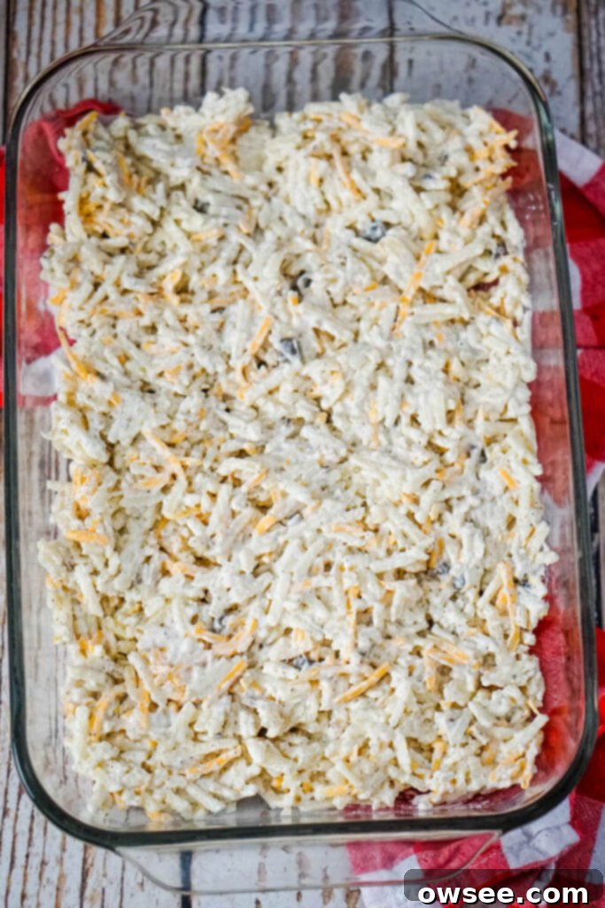 Savory Beef and Hashbrown Bake 8 The first layer of creamy hashbrown mixture being spread evenly across the bottom of a 9x13 casserole dish to form the base.