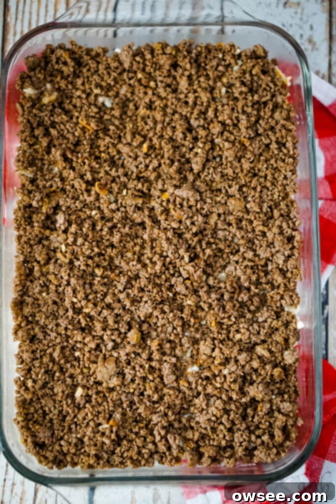 Savory Beef and Hashbrown Bake 9 The savory ground beef filling is spread as the middle layer on top of the hashbrown base in the casserole dish for the Hamburger Hashbrown Casserole.