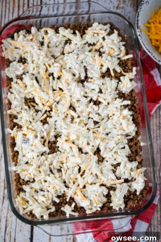Savory Beef and Hashbrown Bake 10 Spoonfuls of the remaining potato mixture are carefully placed over the ground beef layer, forming the top layer of the casserole before baking.