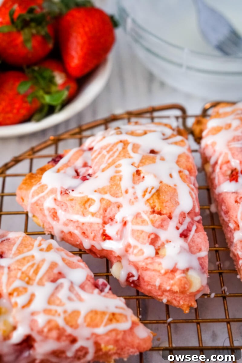 Sweet Strawberry Shortcut Scones 2 A close up image of a strawberry cake mix scone on a wire rack with fresh strawberries in the background.
