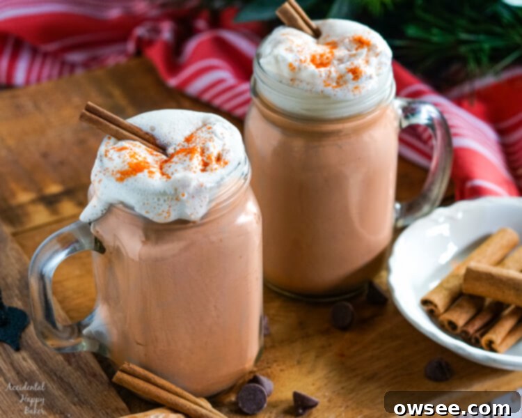 Zesty Cocoa Bliss 3 Clear glass mugs of Mexican Hot Cocoa topped with whipped cream and cinnamon sticks on a wooden tray, showcasing a rich, spiced drink.