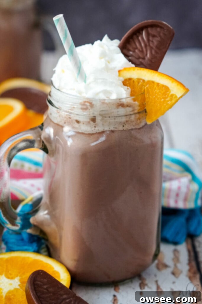 Zesty Cocoa Bliss 5 A close up image of a mug of orange hot chocolate with a colorful striped napkin in the background, showing its rich, creamy texture.