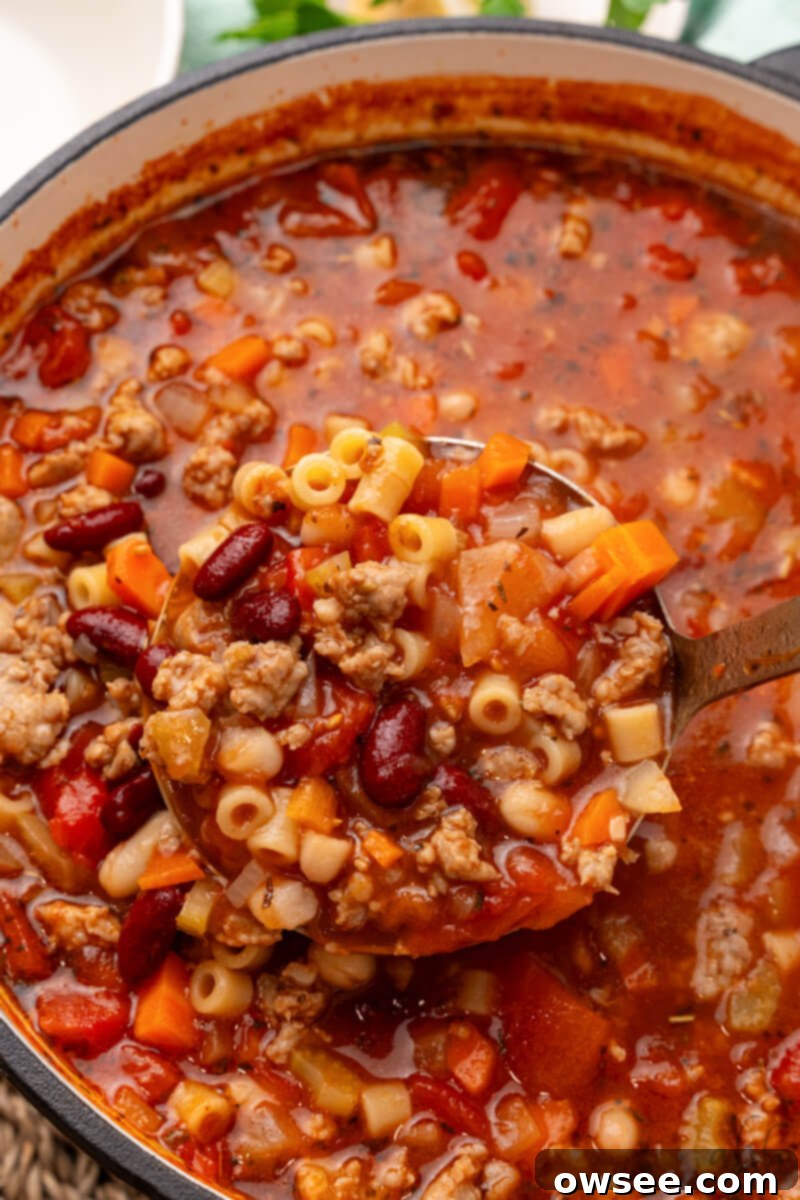 Savory Sausage Pasta Fagioli: An Effortless Comfort 3 A ladle lifts a spoonful of rich Pasta Fagioli with sausage and beans from a large cooking pot, showcasing its hearty texture.