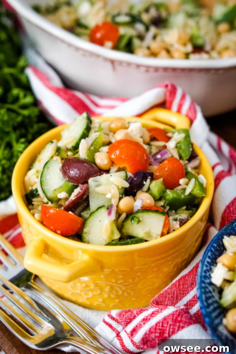 Zesty Orzo Chickpea Salad 2 A serving of Orzo Garbanzo Bean Salad served in a yellow bowl, showcasing its fresh ingredients and vibrant colors.