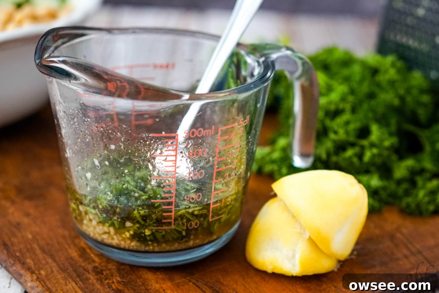 Zesty Orzo Chickpea Salad 7 A glass measuring cup is filled with the homemade salad dressing ingredients, being stirred with a fork to combine.