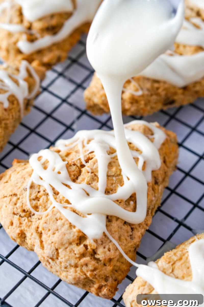 Effortless Carrot Cake Scones 3 The glaze is drizzled over the cooled carrot cake scones on a wire rack.