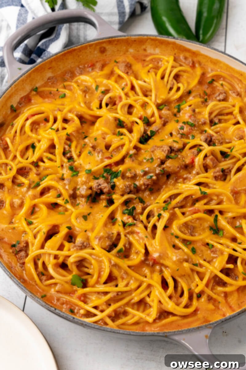 Taco Spaghetti Fiesta 5 A large skillet brimming with freshly made Cheesy Taco Spaghetti, generously topped with vibrant chopped cilantro, highlighting its appealing texture and rich color.