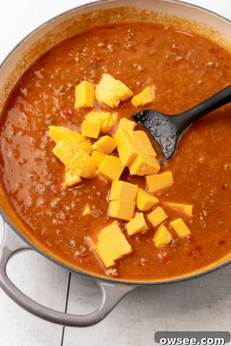 Taco Spaghetti Fiesta 8 Chunks of Velveeta cheese are carefully added to the simmering taco sauce in the skillet and stirred until fully melted and creamy.