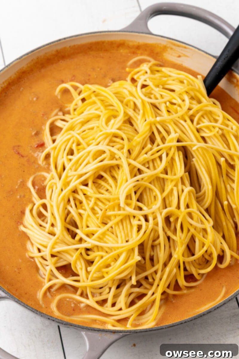 Taco Spaghetti Fiesta 9 Cooked spaghetti noodles are added to the skillet containing the creamy taco meat and cheese sauce, ready to be mixed together.