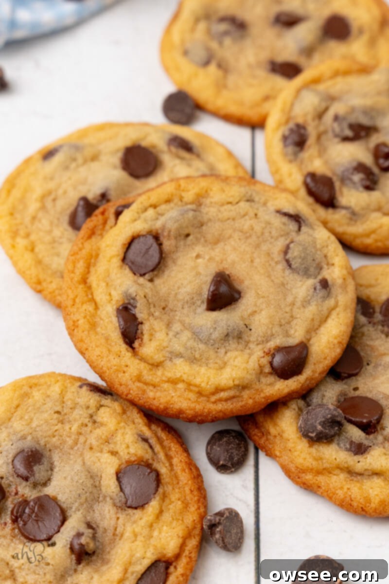 A beautiful pile of freshly baked Malted Chocolate Chip Cookies, golden brown with visible chocolate chips, cooling on a table.